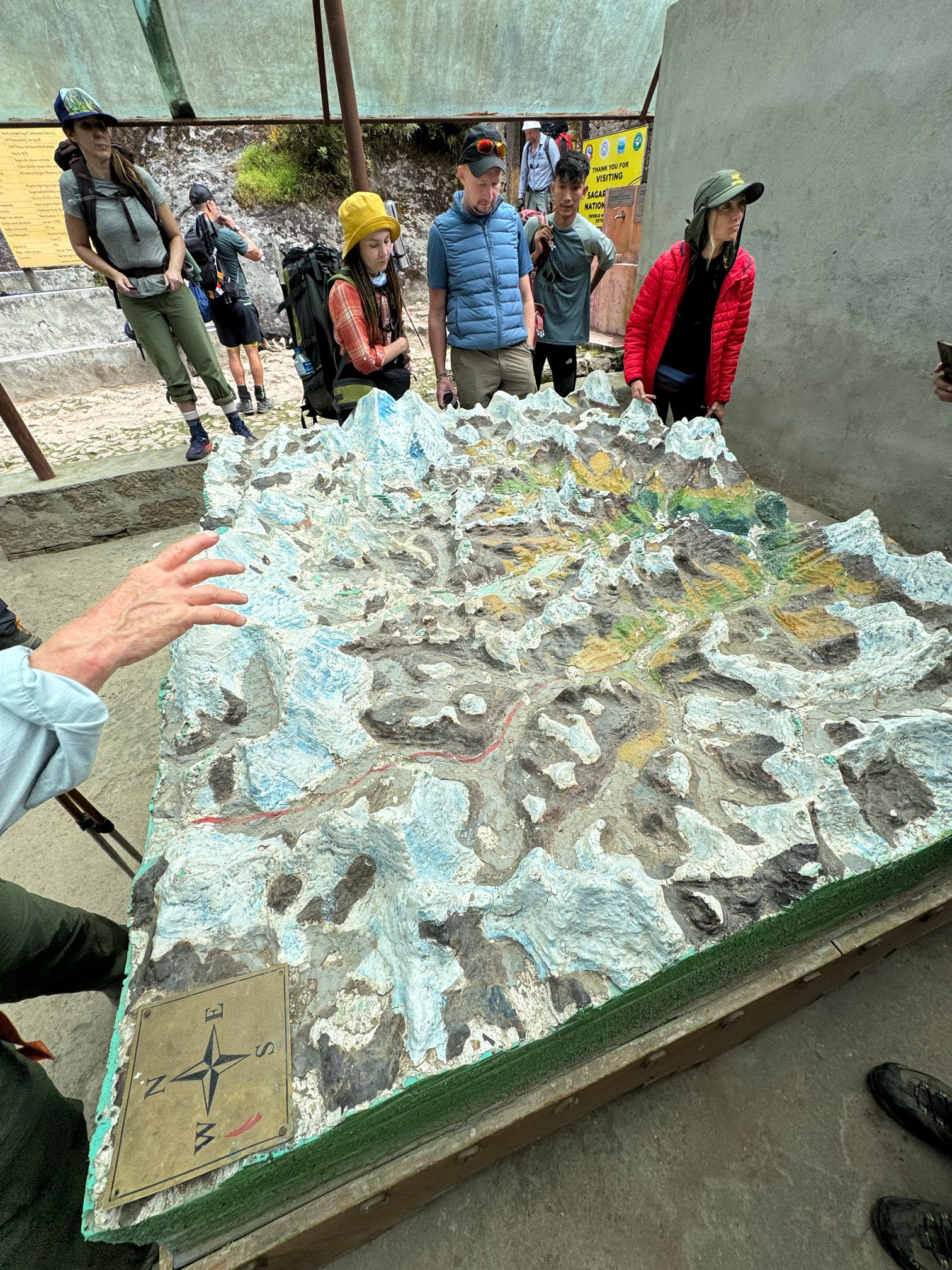 trekker checking a trail distance model marked to upcoming villages to get the answer quick on how far Is the Everest Base Camp Trek